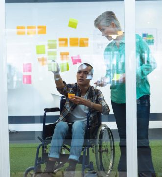 Male and female executives discussing over sticky notes in office